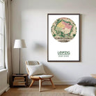 a living room with a wooden chair, a lamp, and a framed map of Leipzig, Germany, which is a city in the state of Bavaria.