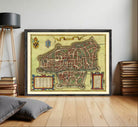 The image is a framed antique map of a city, likely from the Middle Ages, with intricate details and a decorative border.