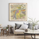 a large framed map of a city hanging on a wall above a couch with pillows and a coffee table in a living room setting.