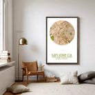 a living room with a large framed map of San Jose, California, hanging on the wall. The room has a wooden chair, a lamp, and some books on a shelf.