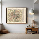 a large framed map of the city of Paris hanging on the wall, with a wooden table and lamp below it.