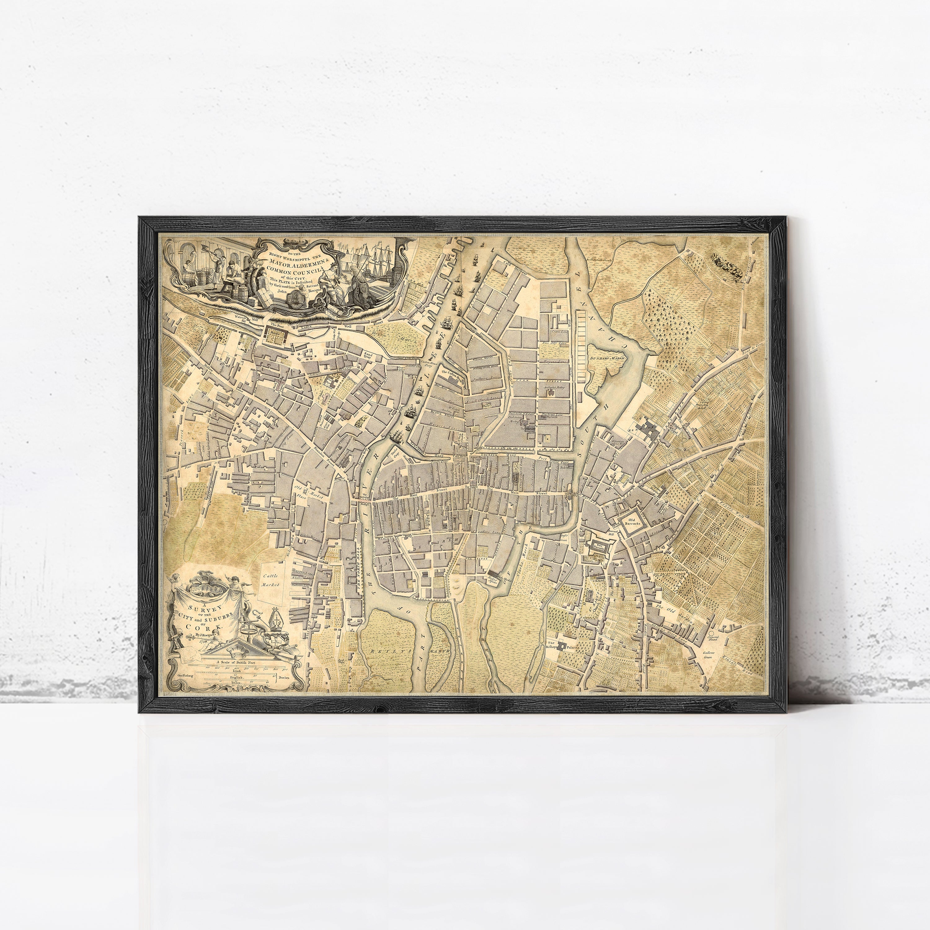 The image is a framed antique map of a city, likely from the 16th century, displayed on a white wall.