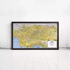 The image is a large framed map of Los Angeles, California, with various landmarks and cityscapes depicted.