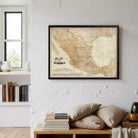 a framed map of Mexico hanging on a wall, with a bookshelf filled with books and various decorative items below it.