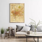 a living room with a large framed map of Rome hanging on the wall above a couch with pillows. The room also includes a coffee table with books and a vase with greenery.