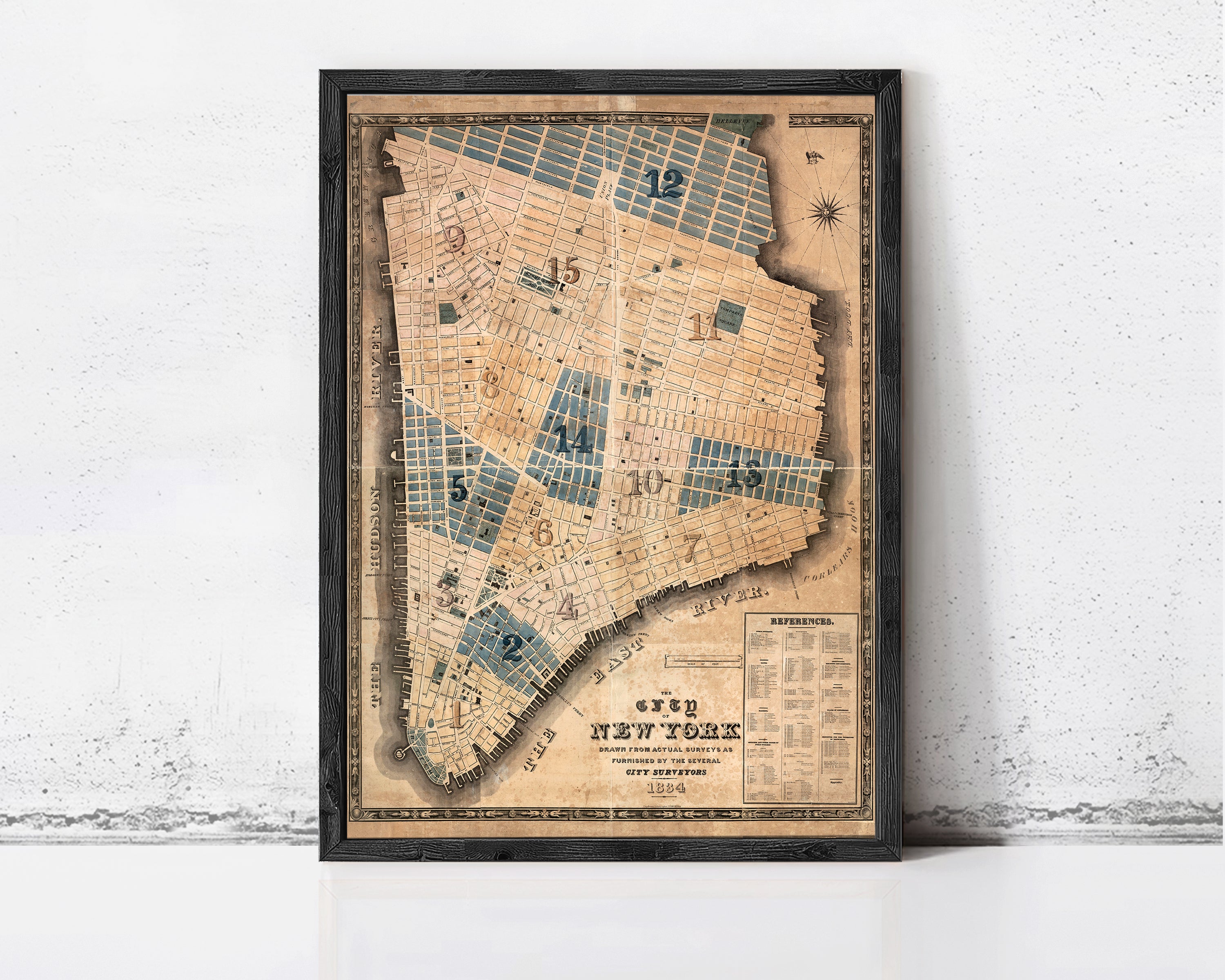 The image is a framed vintage map of New York City, depicting the city's streets and neighborhoods in a detailed and intricate manner.