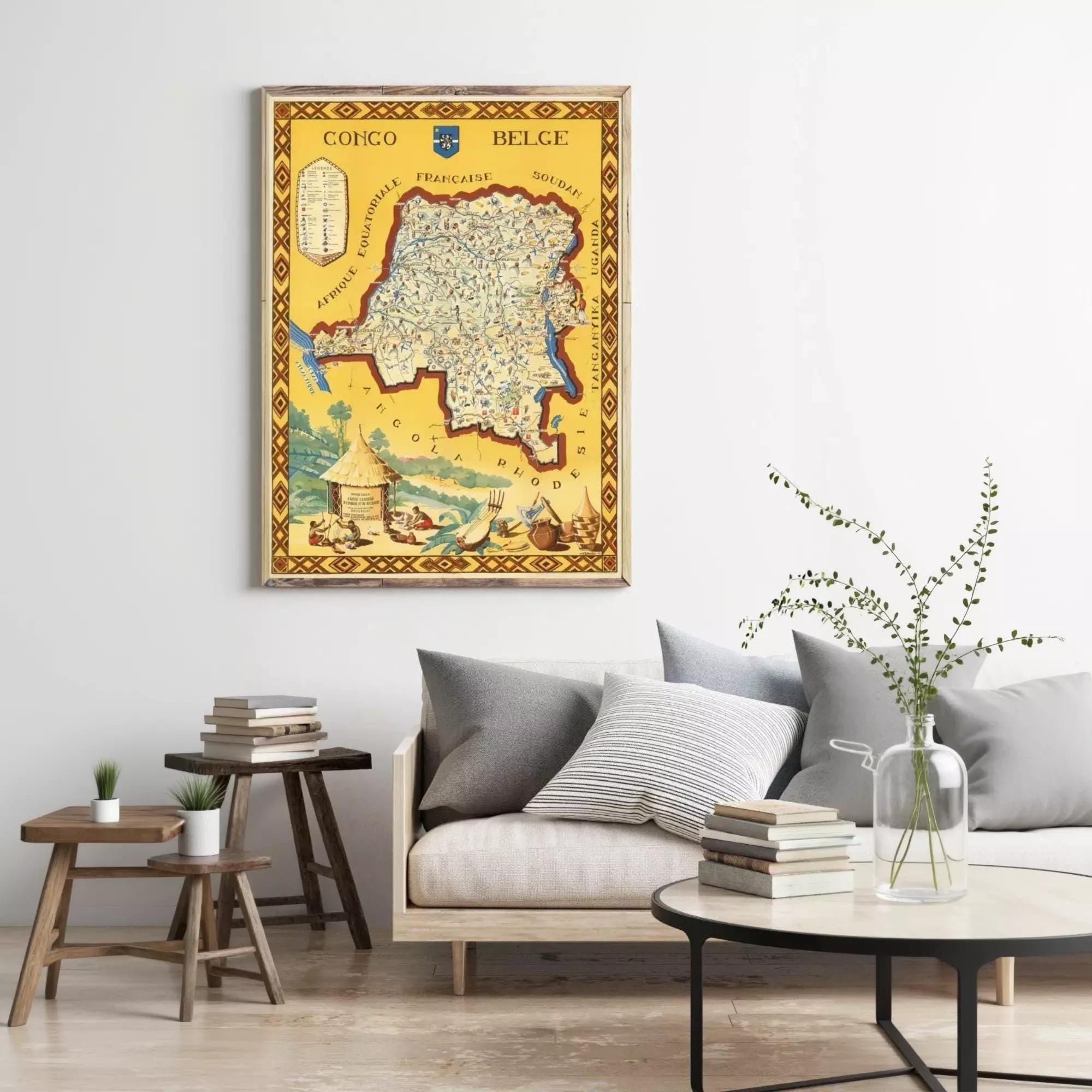 a living room with a large framed map of the country of Congo hanging on the wall. The room has a gray couch, a coffee table with books and a vase of greenery, and a wooden stool.