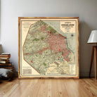 The image is a framed vintage map of a city, likely from the early 20th century, depicting a detailed layout of the city's streets, landmarks, and surrounding areas.
