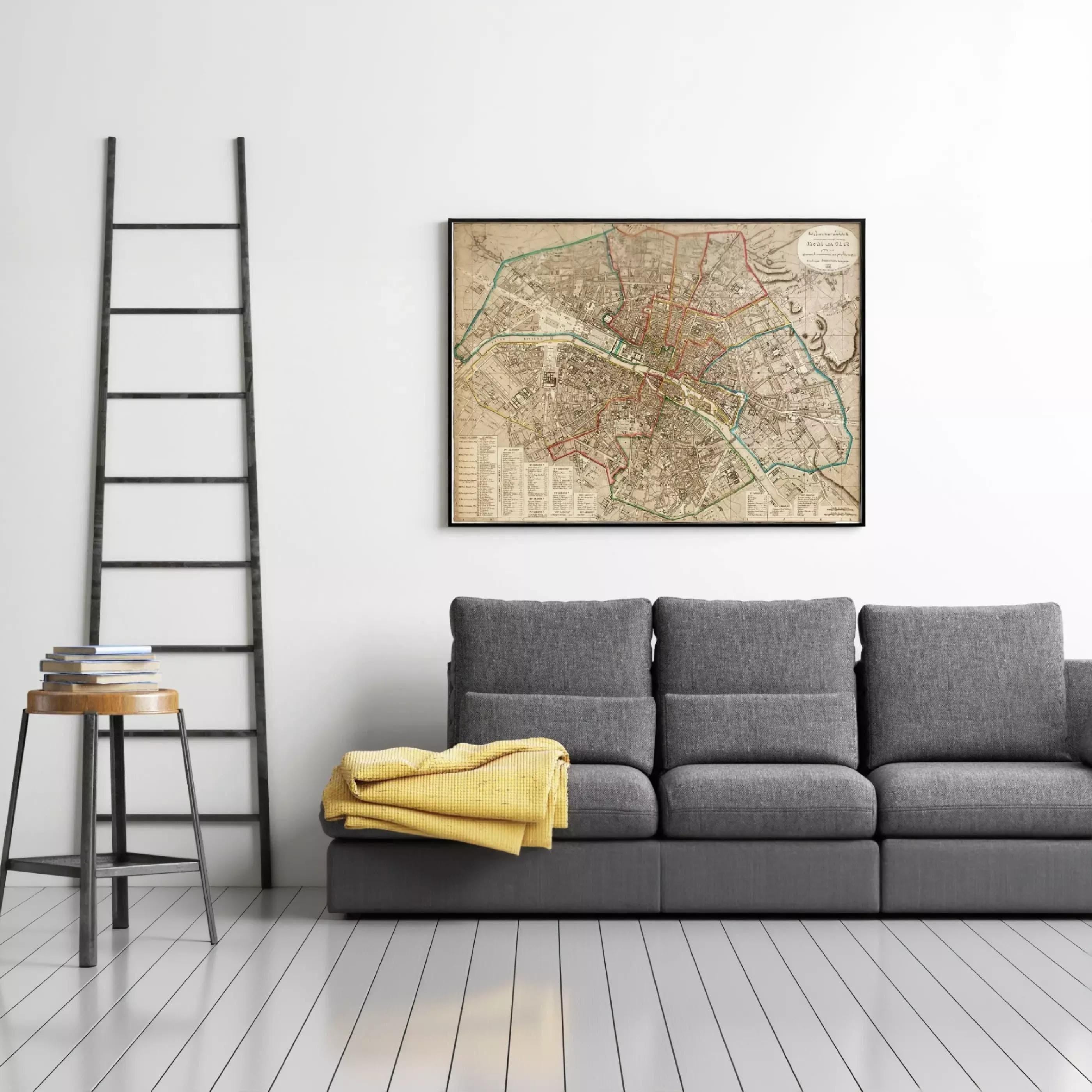 a gray sofa with a yellow blanket draped over it, and a black ladder leaning against the wall next to the sofa. Above the sofa, there is a framed map hanging on the wall.