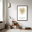 a cozy corner of a room with a wooden chair, a lamp, and a framed map of Rochester, New York.