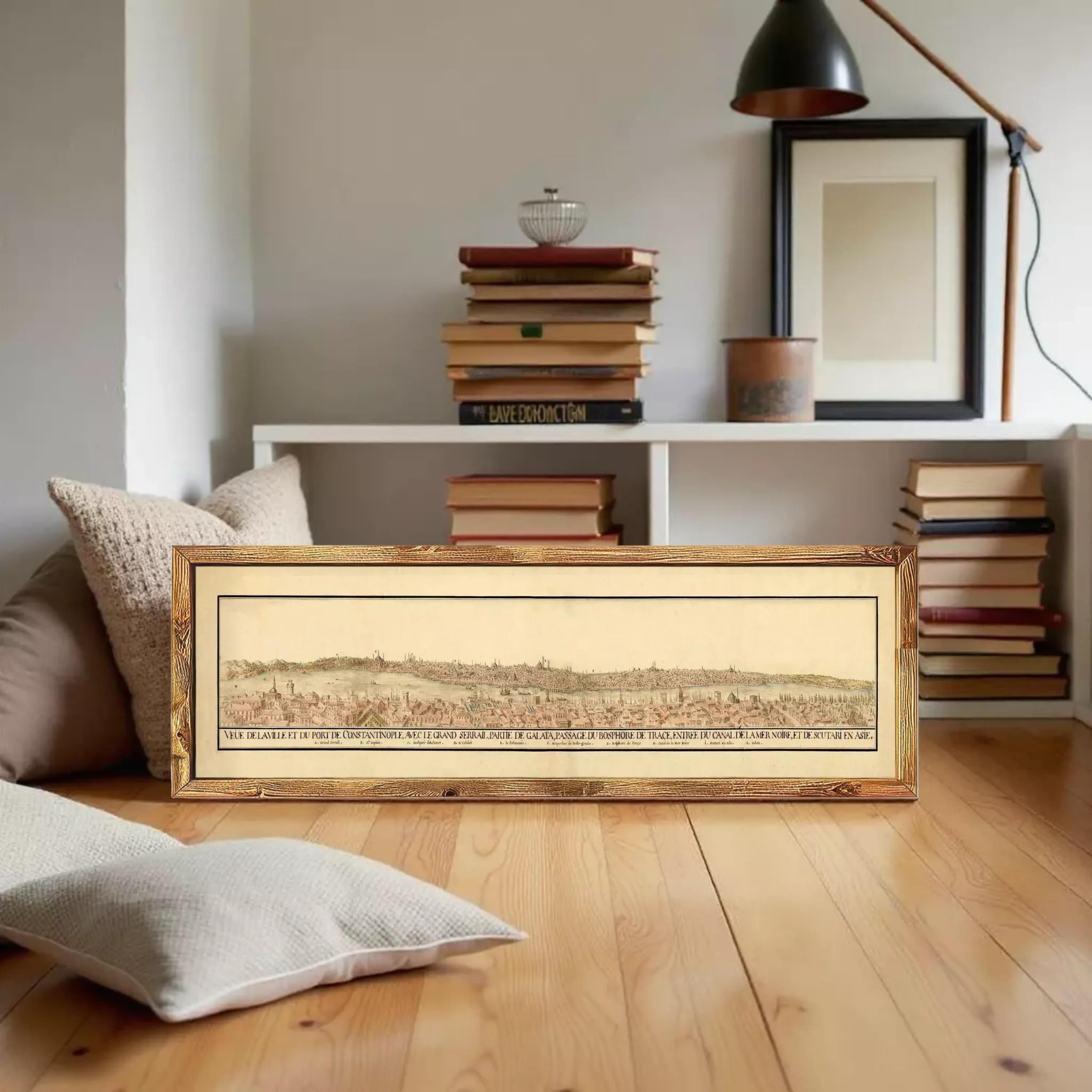 A framed print of a historical map depicting a cityscape is displayed against a white wall.