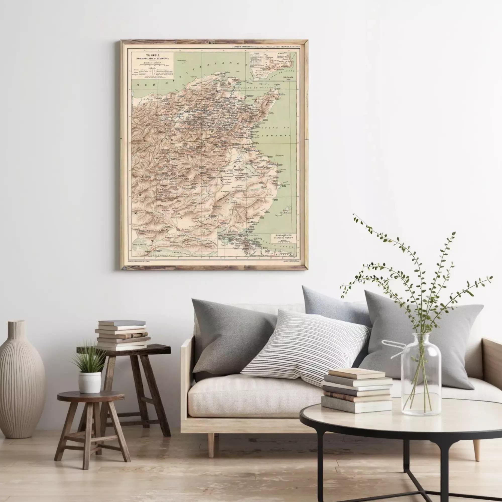 a living room with a large map of China hanging on the wall above a couch with pillows. The room has a wooden floor, a coffee table with books and a vase of greenery, and a small table with a plant.