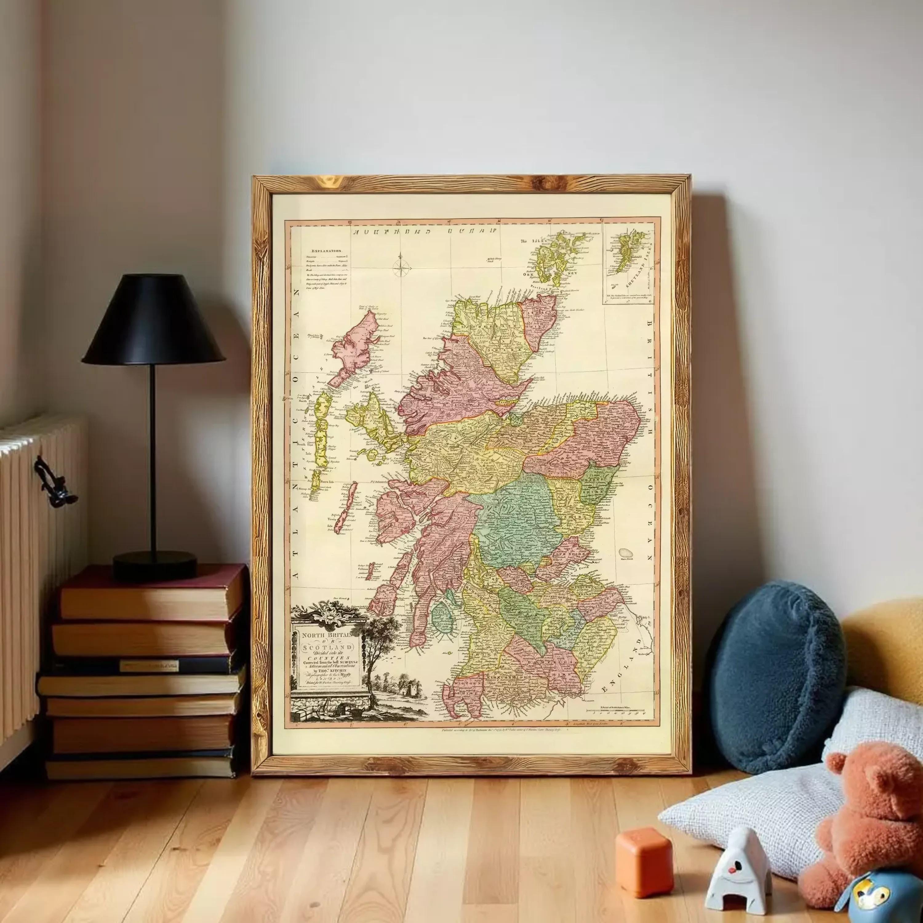 a large framed map of Scotland, with a black lamp and a stack of books on the left side of the frame.