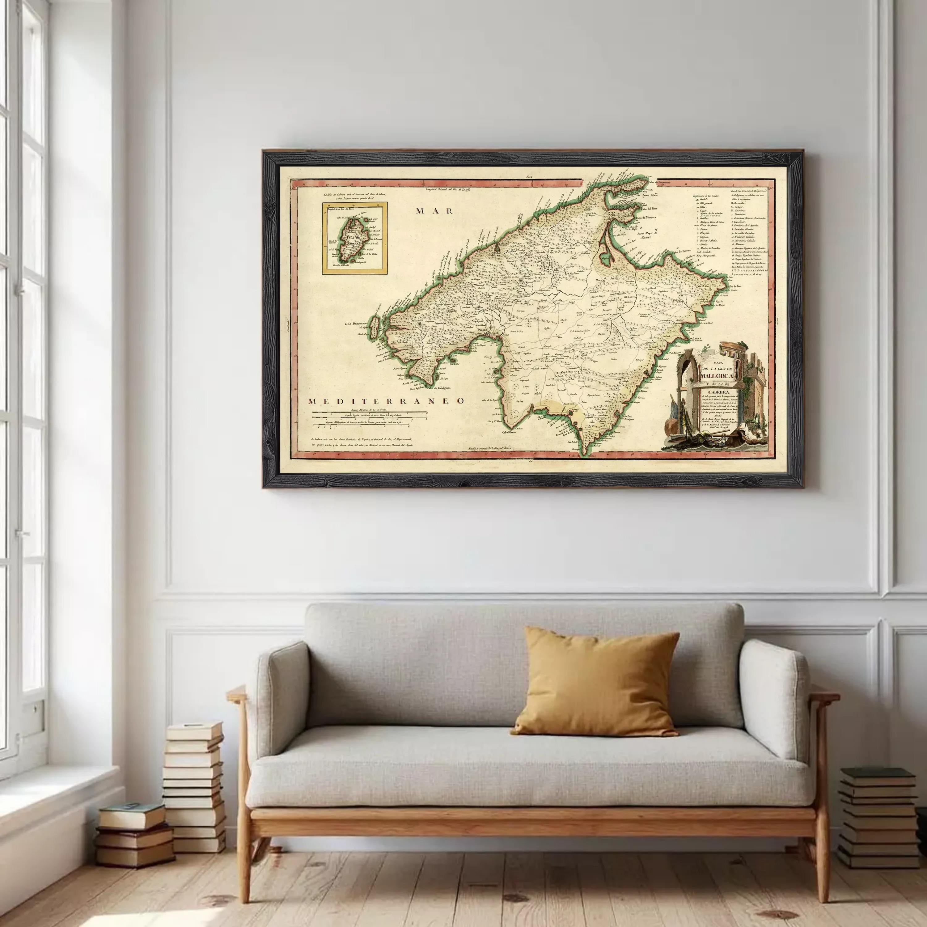 a large framed map of the Mediterranean region hanging on a wall above a gray sofa with a single yellow throw pillow.