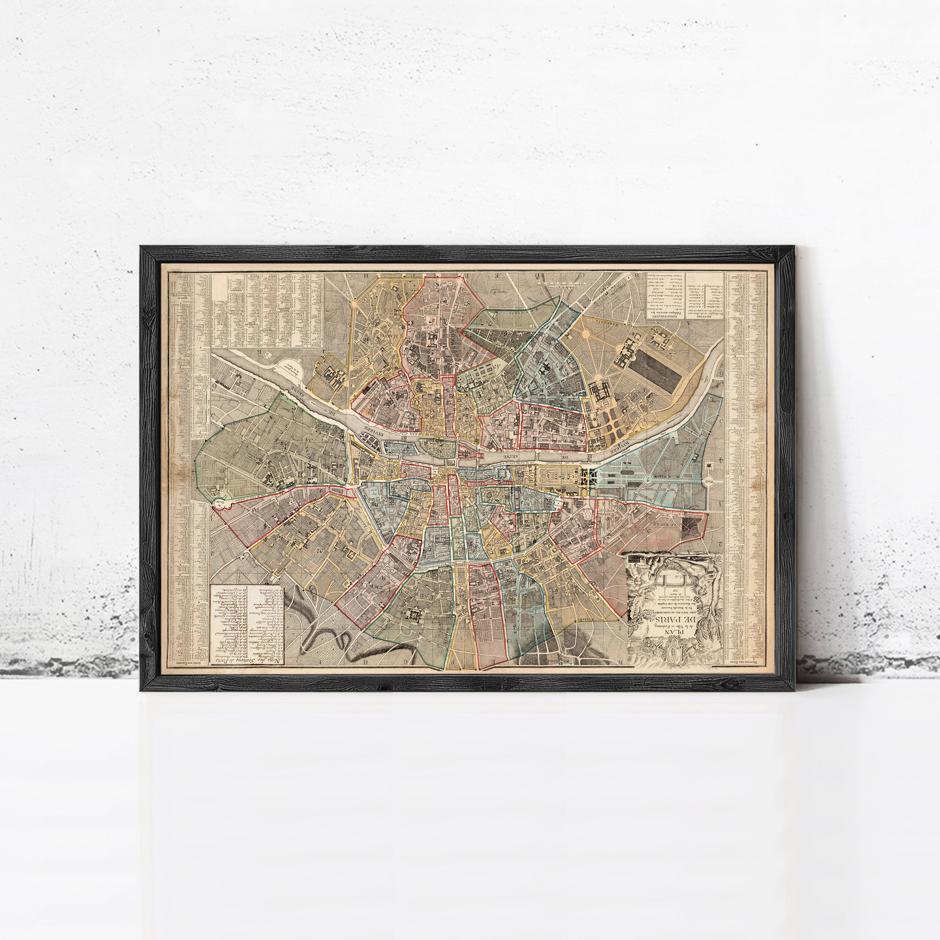 The image is a framed vintage map of a city, likely from the 19th century, displayed on a white wall.