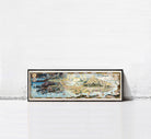 A large, colorful, and detailed map of a coastal region or island, displayed in a frame against a plain white wall.