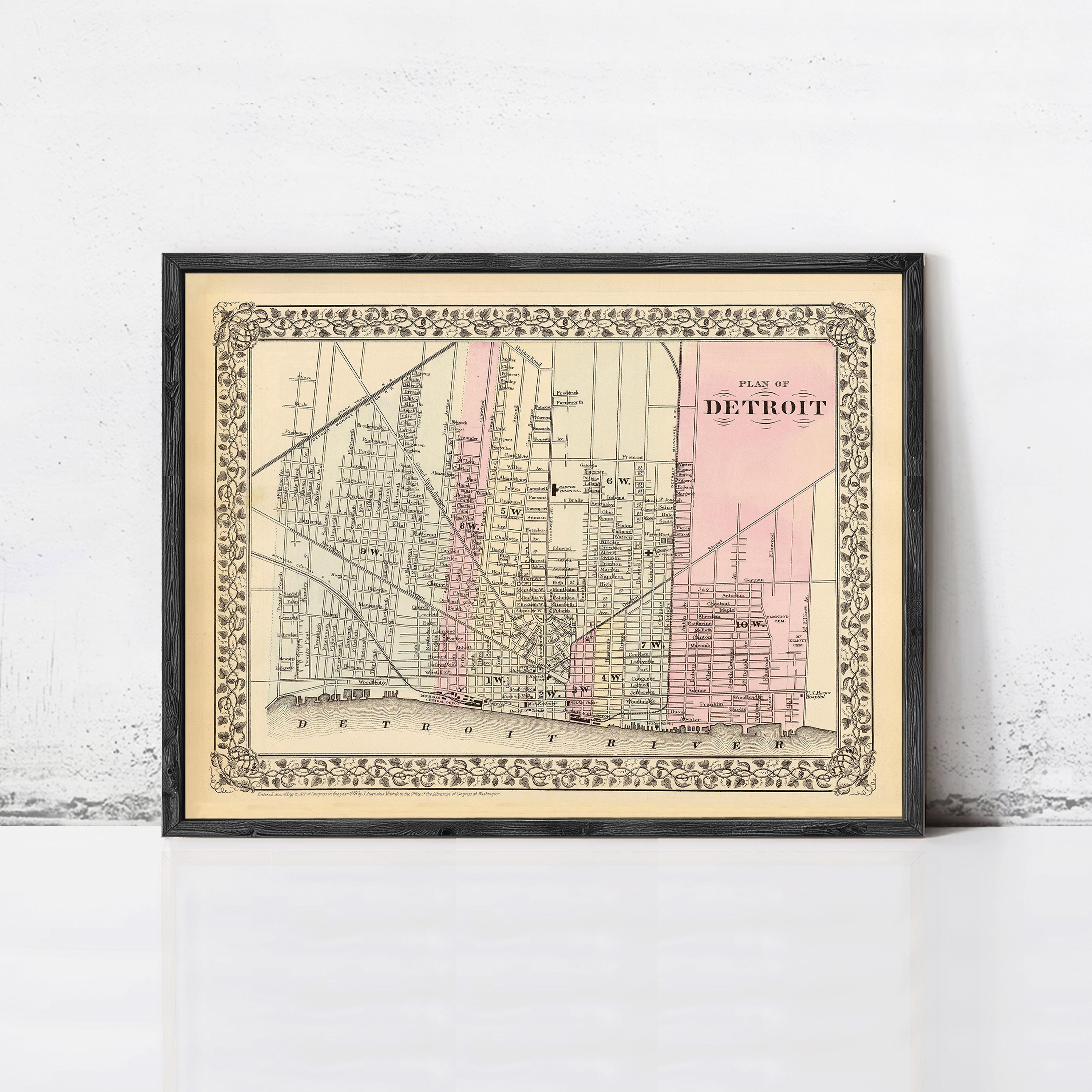 The image is a framed vintage map of Detroit, Michigan, depicting the city's streets and landmarks.