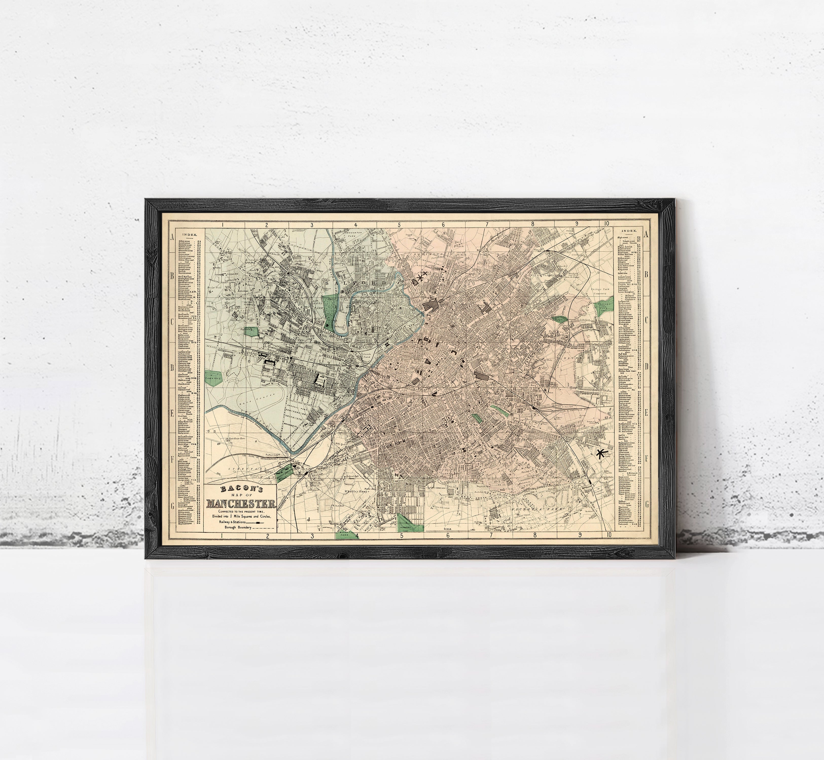 The image is a framed vintage map of a city, likely from the early 20th century, displayed on a white wall.
