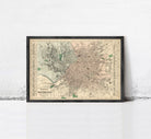 The image is a framed vintage map of a city, likely from the early 20th century, displayed on a white wall.