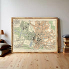 a large framed map of a city, with a wooden floor and a stack of books to the right.