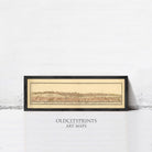 The image is a framed art print depicting a historical map of a city, with a white wall in the background.