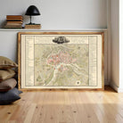 a large framed map of a city, with a wooden shelf and a lamp in the background.