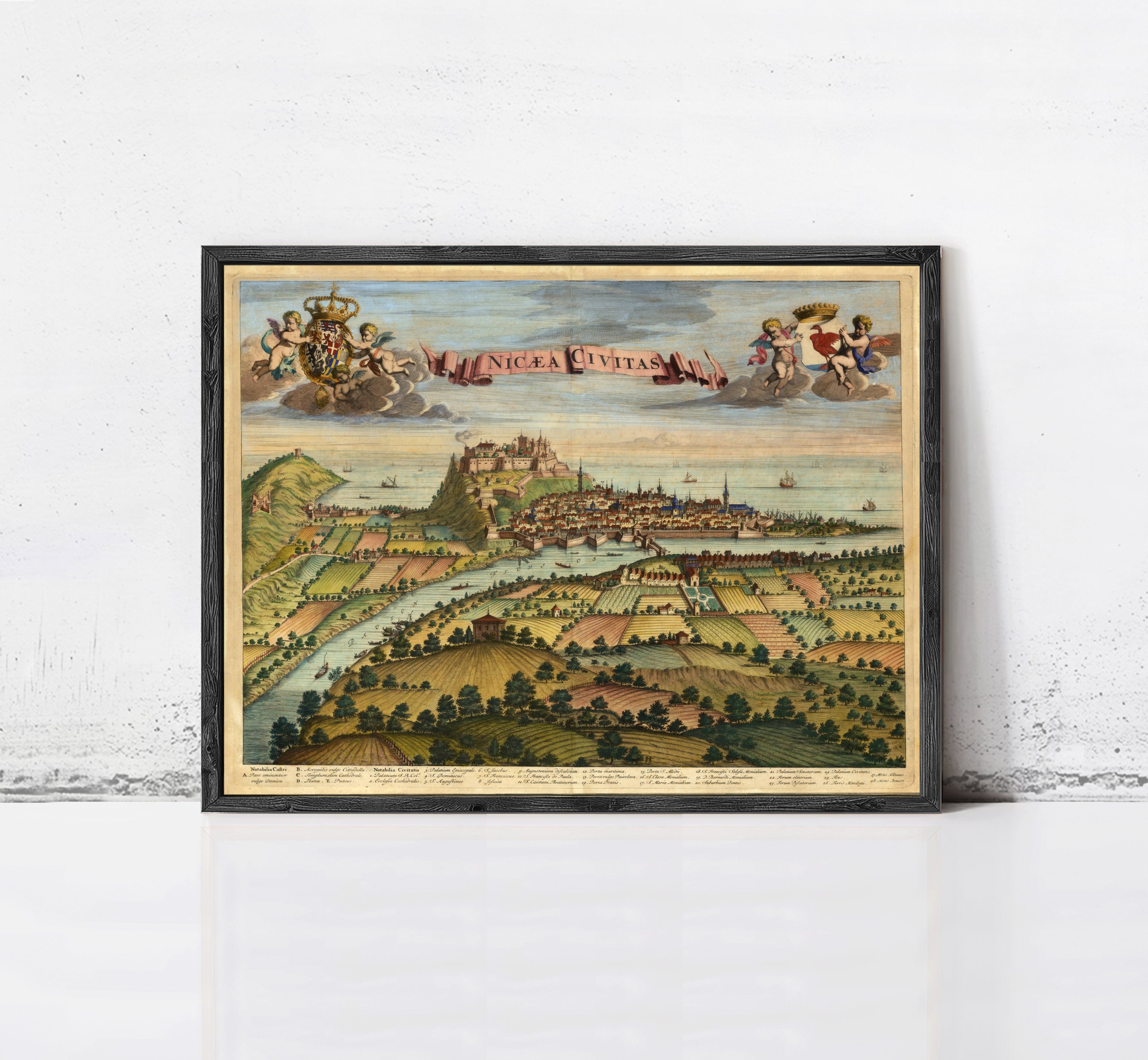 The image is a framed vintage map of a city, depicting a landscape with a river, buildings, and people.
