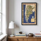 a framed map of Argentina hanging on a wall above a wooden cabinet. The cabinet has a lamp on top of it and several books and decorative items placed on the surface below the cabinet.