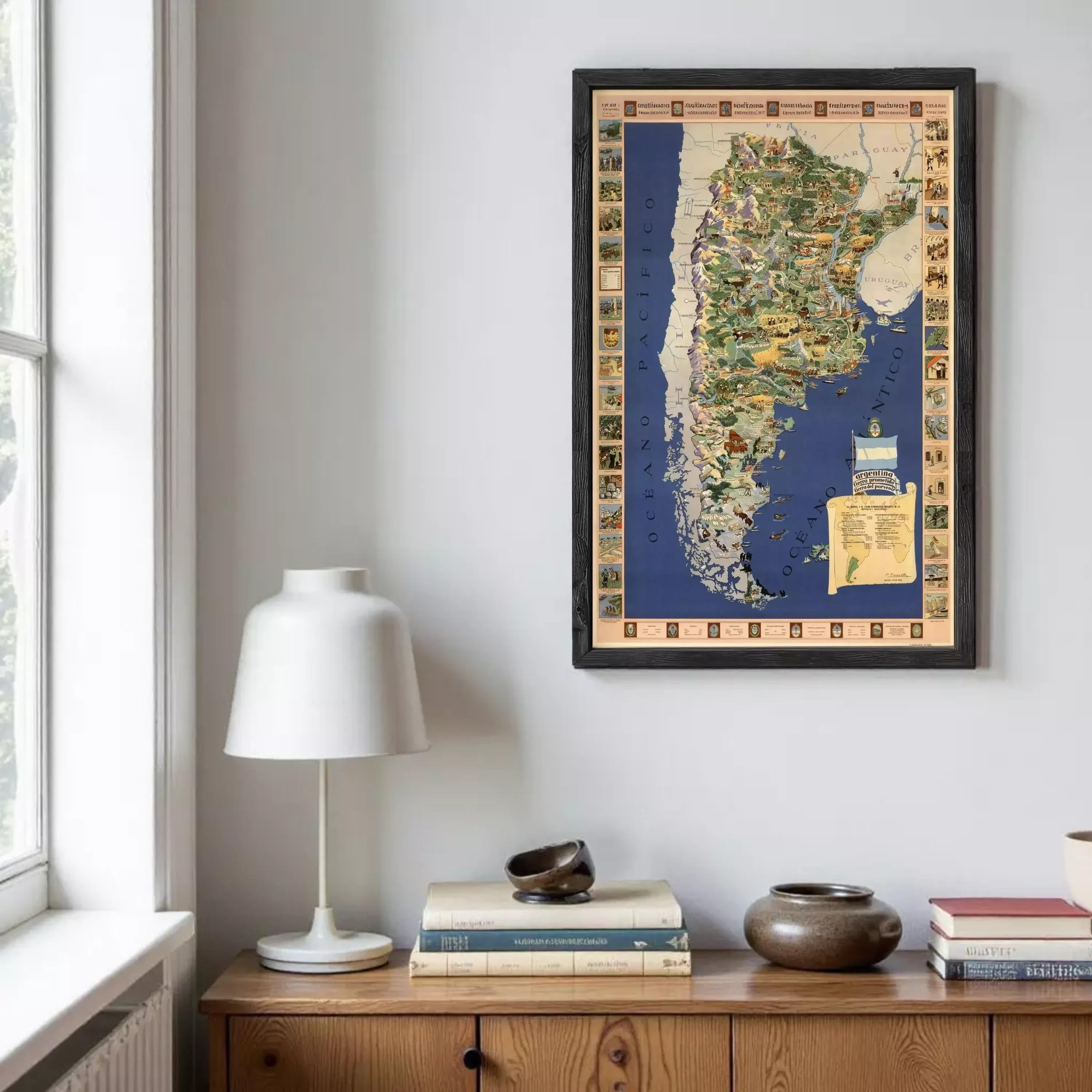 a framed map of Argentina hanging on a wall above a wooden cabinet. The cabinet has a lamp on top of it and several books and decorative items placed on the surface below the cabinet.
