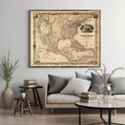 a large framed map of the United States hanging on a wall above a couch with pillows and a coffee table in a living room setting.