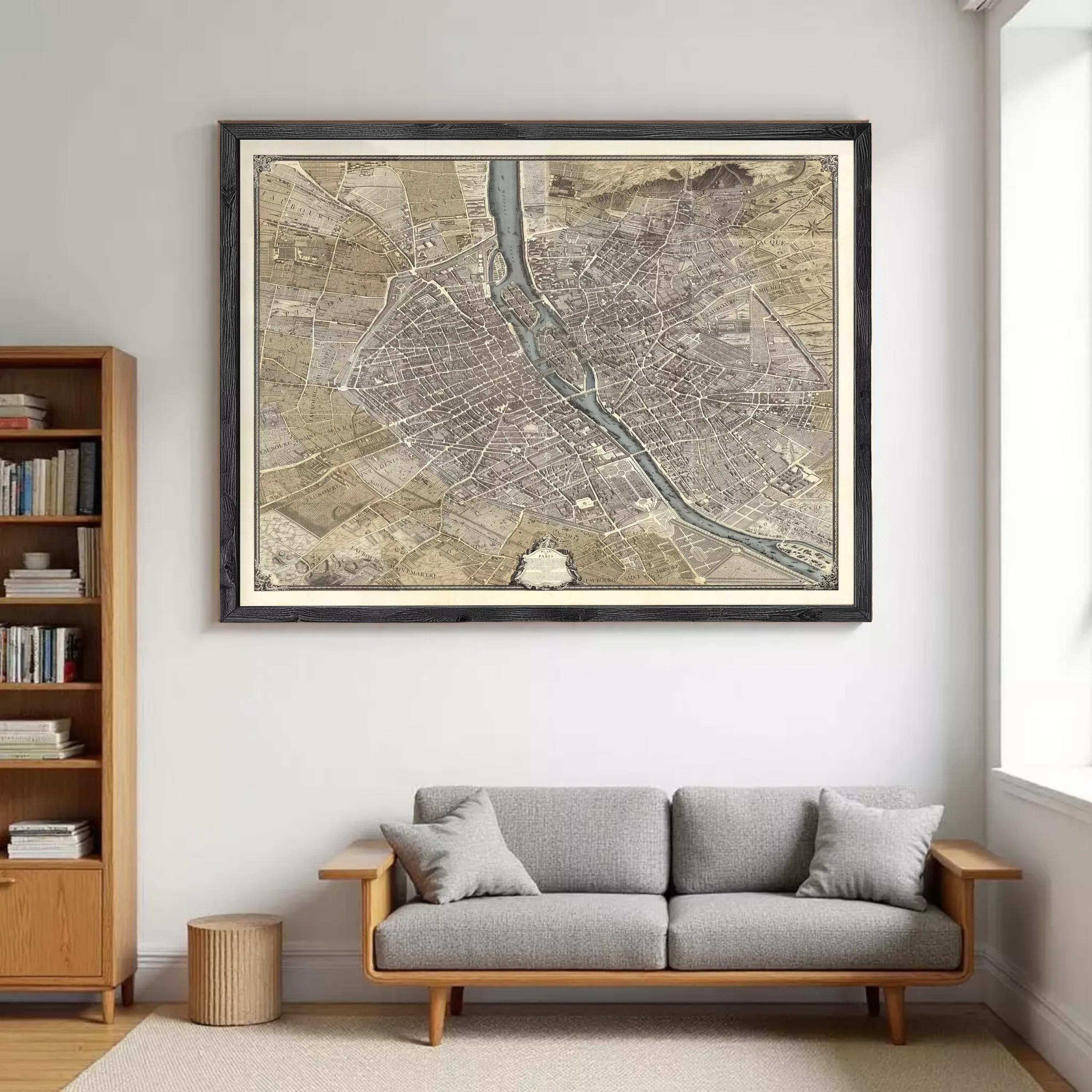 a large framed map of a city hanging on a wall above a gray sofa in a living room.