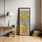 a colorful, abstract painting of a swirling pattern, which is hanging on a wall next to a wooden table with a lamp and a stack of books.