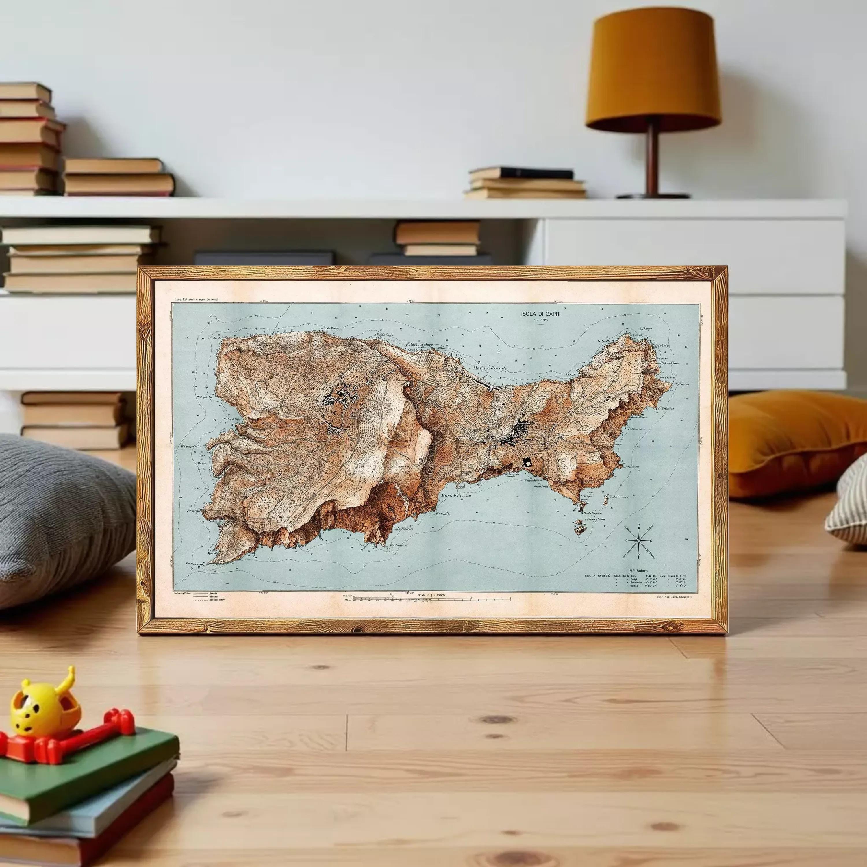 A framed map of a mountainous region is displayed on a wooden floor, surrounded by various books and a lamp.