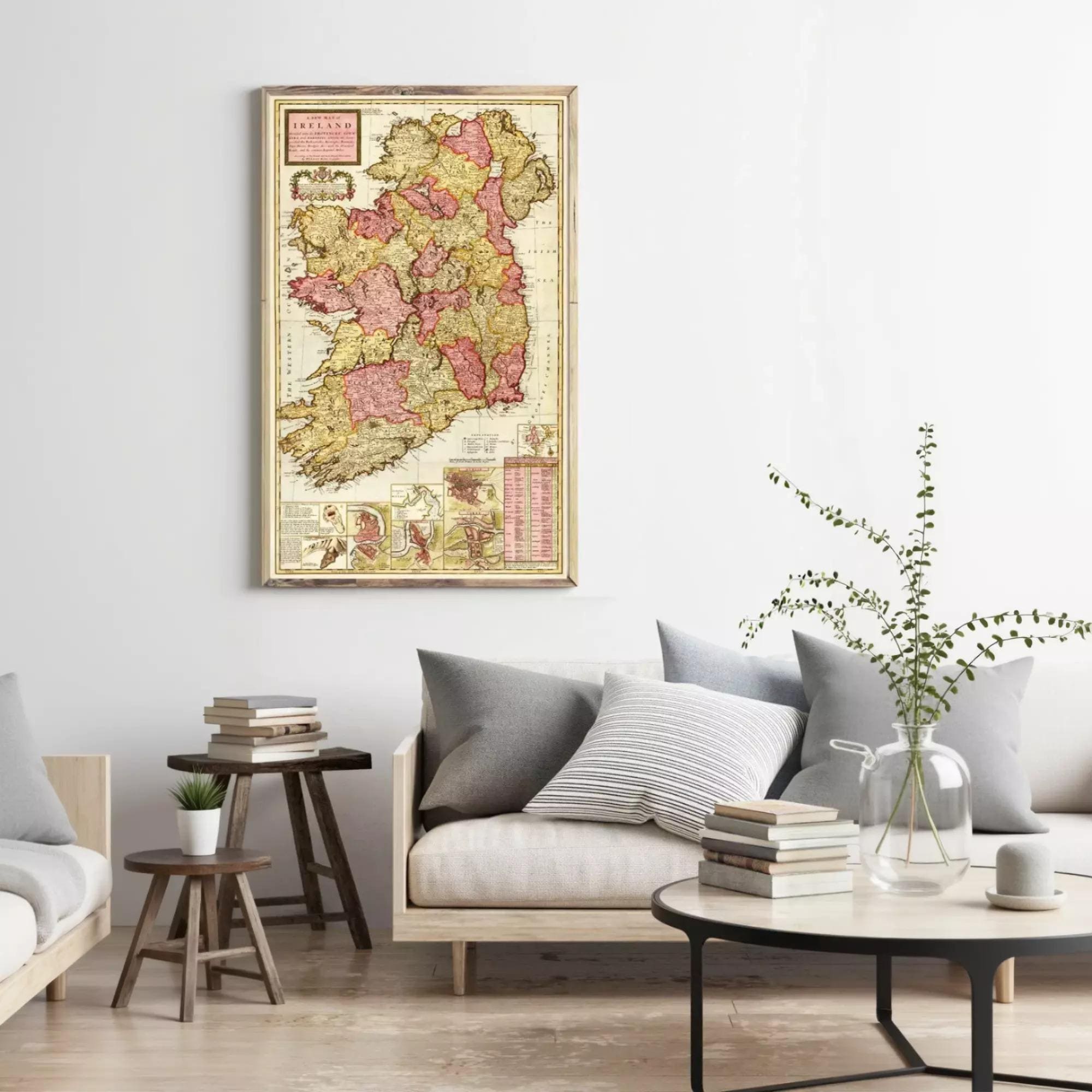 a living room with a large framed map of Ireland hanging on the wall above a gray sofa with striped pillows. The room also includes a coffee table with books and a vase of greenery.