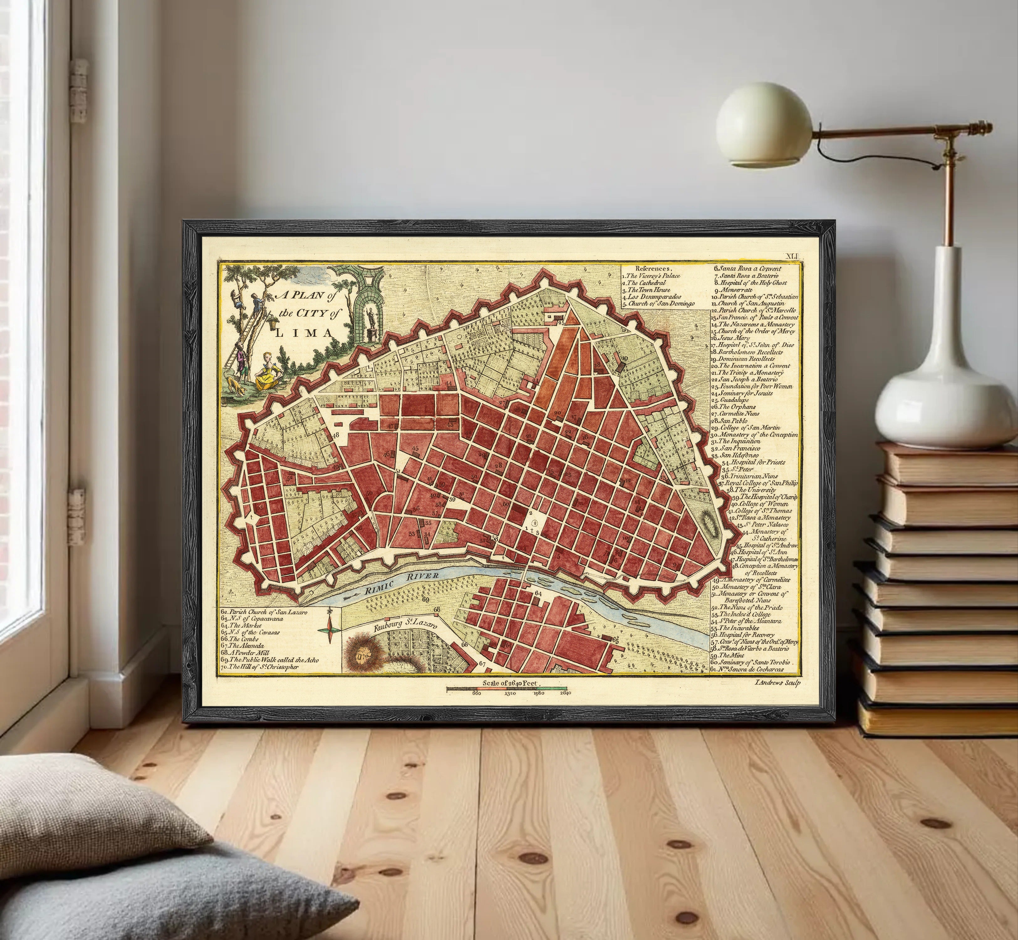 a framed map of a city, with a lamp and books on a shelf in the background.