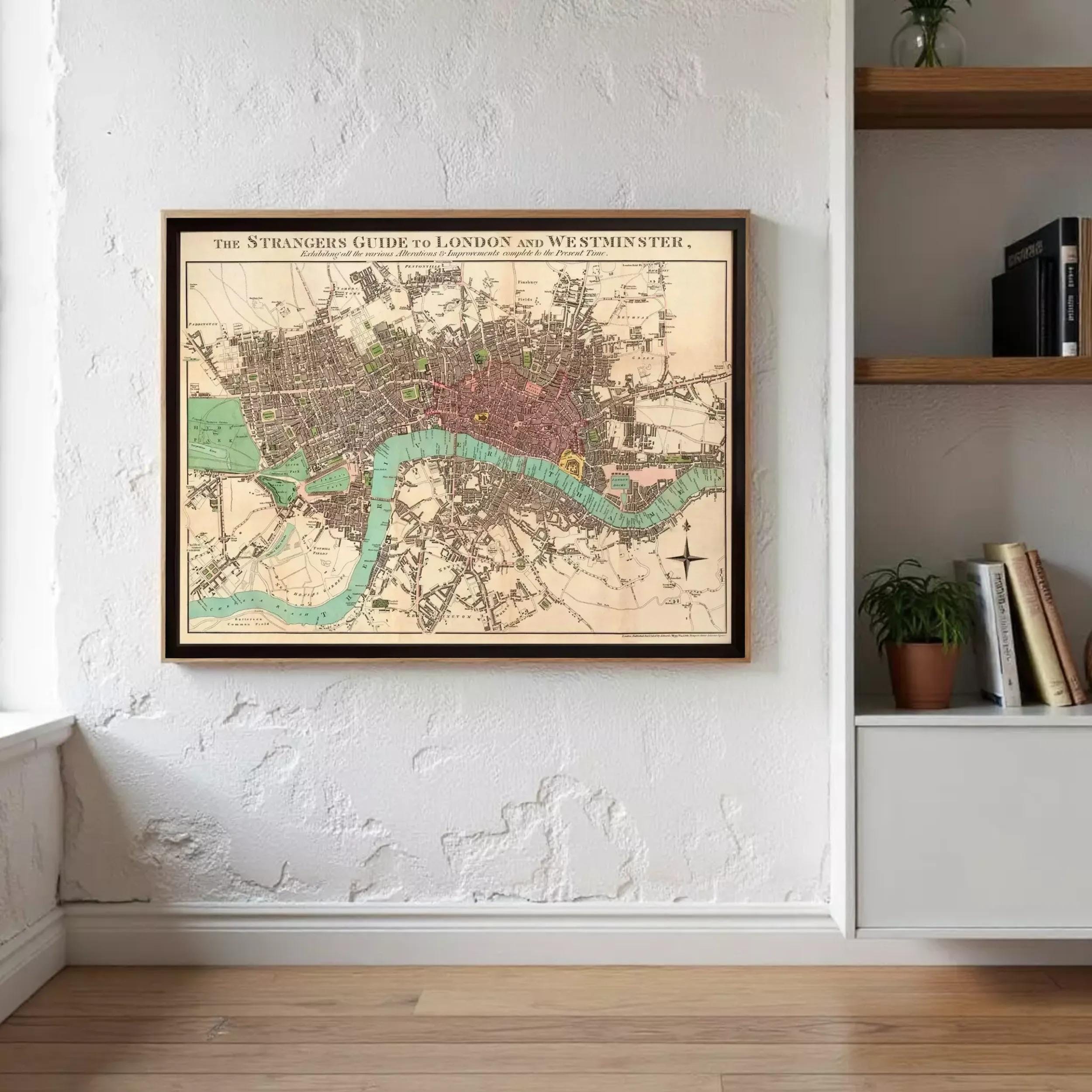 a framed map of London and Westminster, with a wooden shelf and a plant in the background.