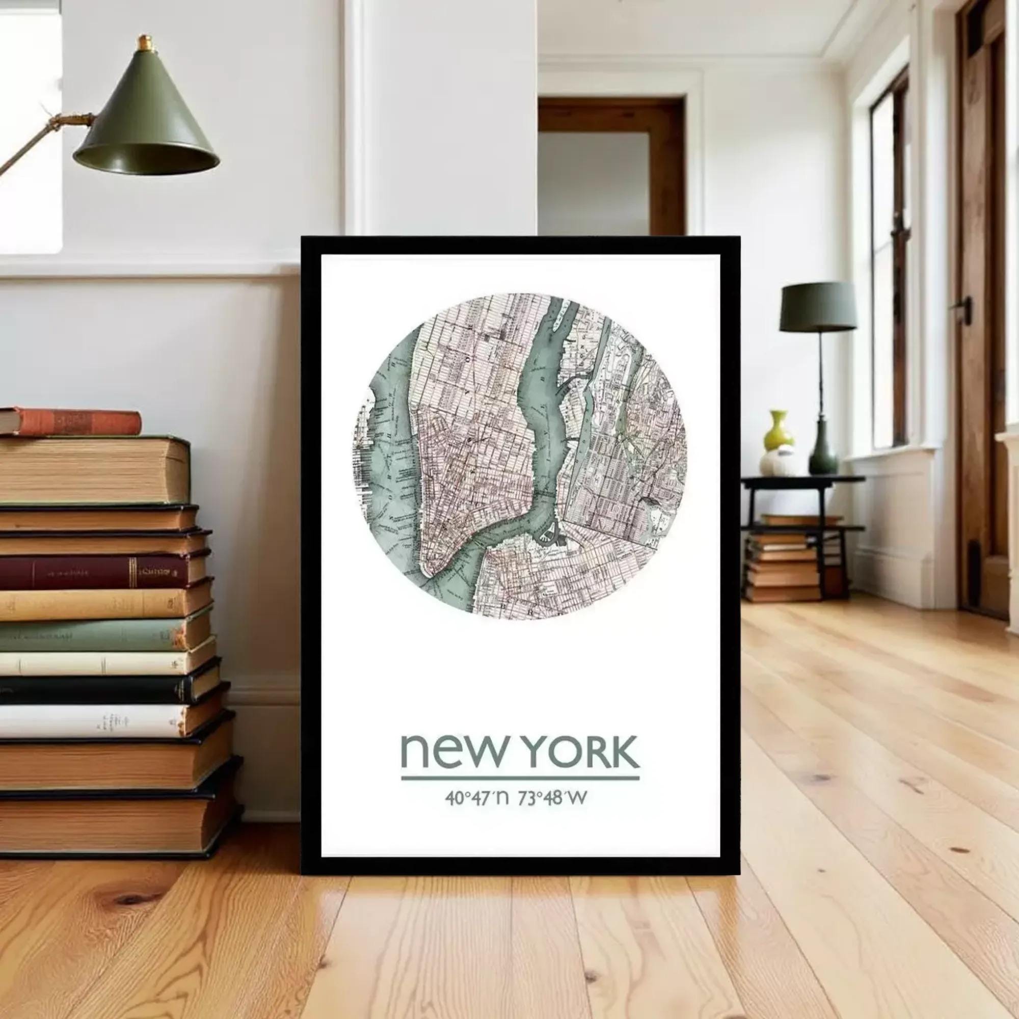 A framed map of New York City with a green and brown color scheme, depicting the city's streets and landmarks, is displayed on a wooden floor in a room with books and a lamp.