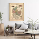 a living room with a large framed map of Denmark hanging on the wall above a couch with pillows. The room has a wooden coffee table, a plant, and some books on a side table.