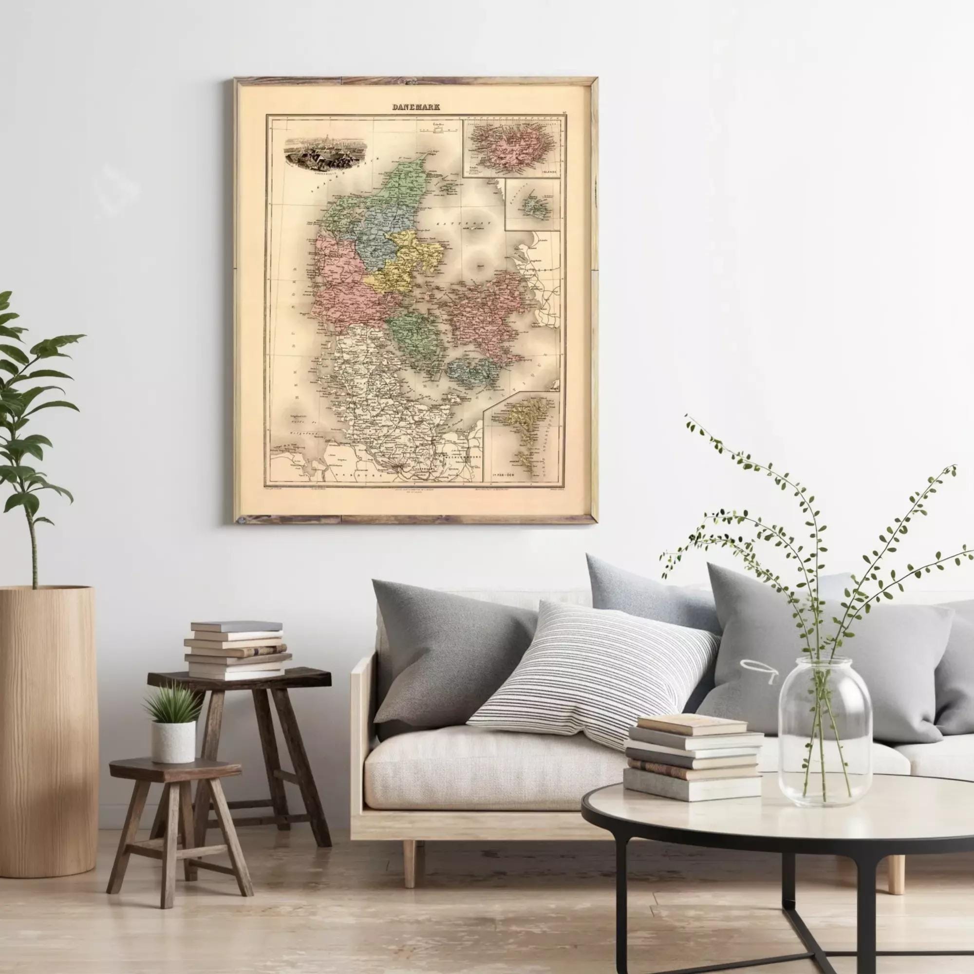a living room with a large framed map of Denmark hanging on the wall above a couch with pillows. The room has a wooden coffee table, a plant, and some books on a side table.