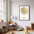 a cozy living room with a large framed map of Buffalo, New York, hanging on the wall. The room is furnished with a wooden chair, a lamp, and a stack of books. There are also some toys and decorative items in the room, creating a warm and inviting atmosphere.