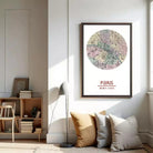 a living room with a framed map of Paris hanging on the wall, a bookshelf, a lamp, and some pillows.