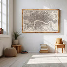 a large framed map of London hanging on a white wall, with a wooden chair and a stack of books placed nearby.
