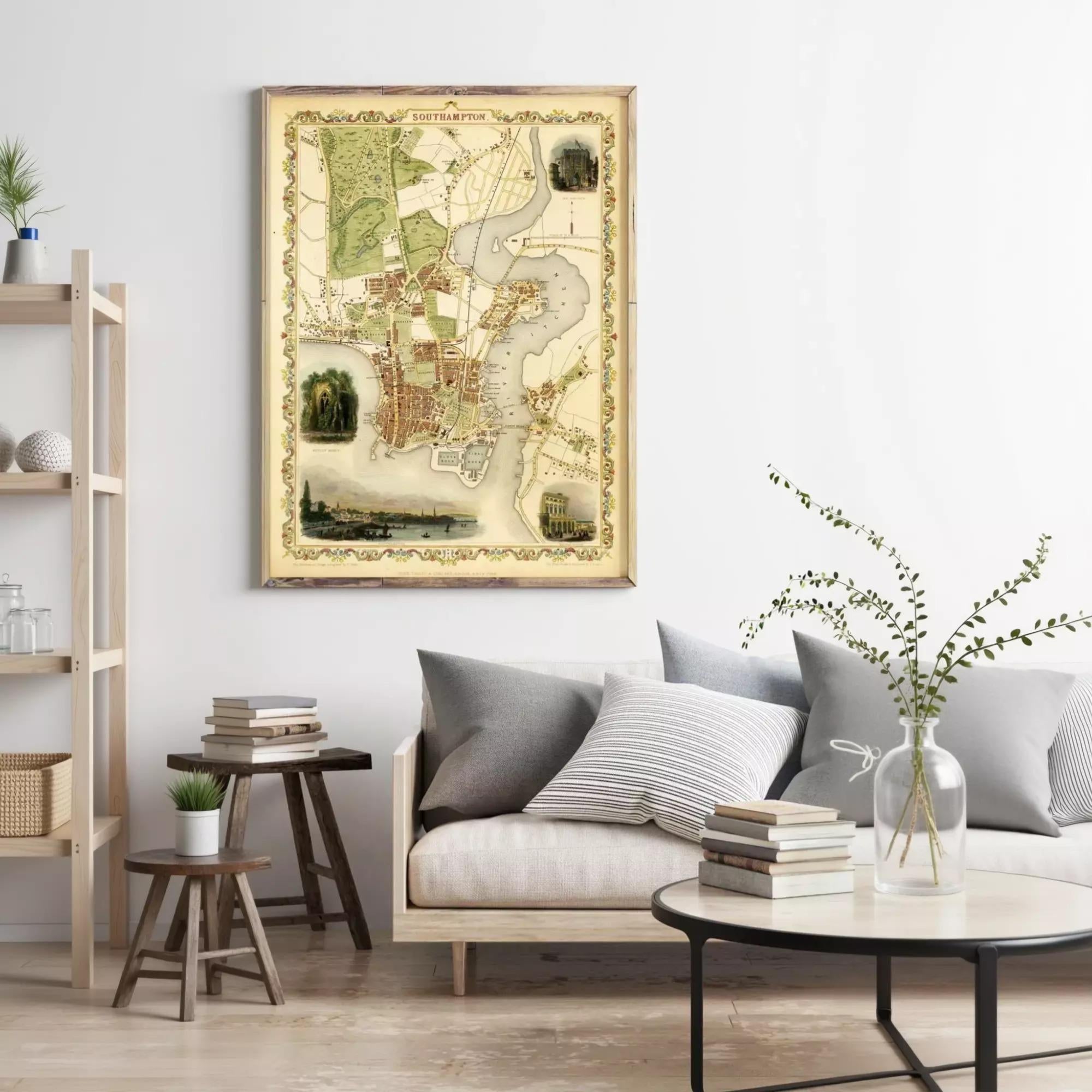 a living room with a large framed map hanging on the wall, a couch with pillows, a coffee table with books, and a plant in a vase.