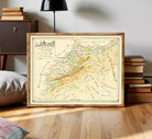The image is a framed vintage map of a region, likely depicting a mountainous area. The map is framed in a wooden frame and is displayed on a white wall.