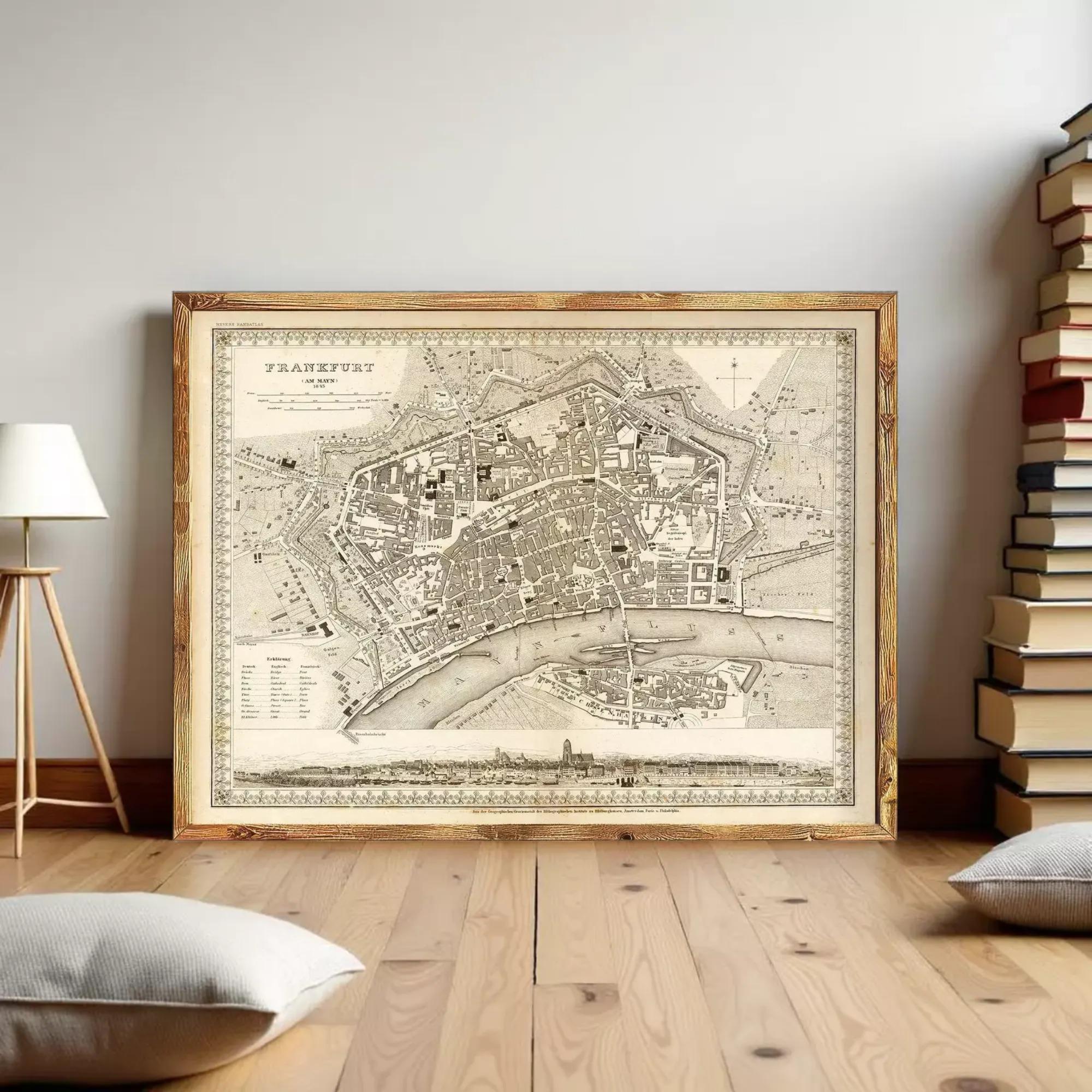 a large framed map of a city, with a wooden floor and a stack of books in the background.