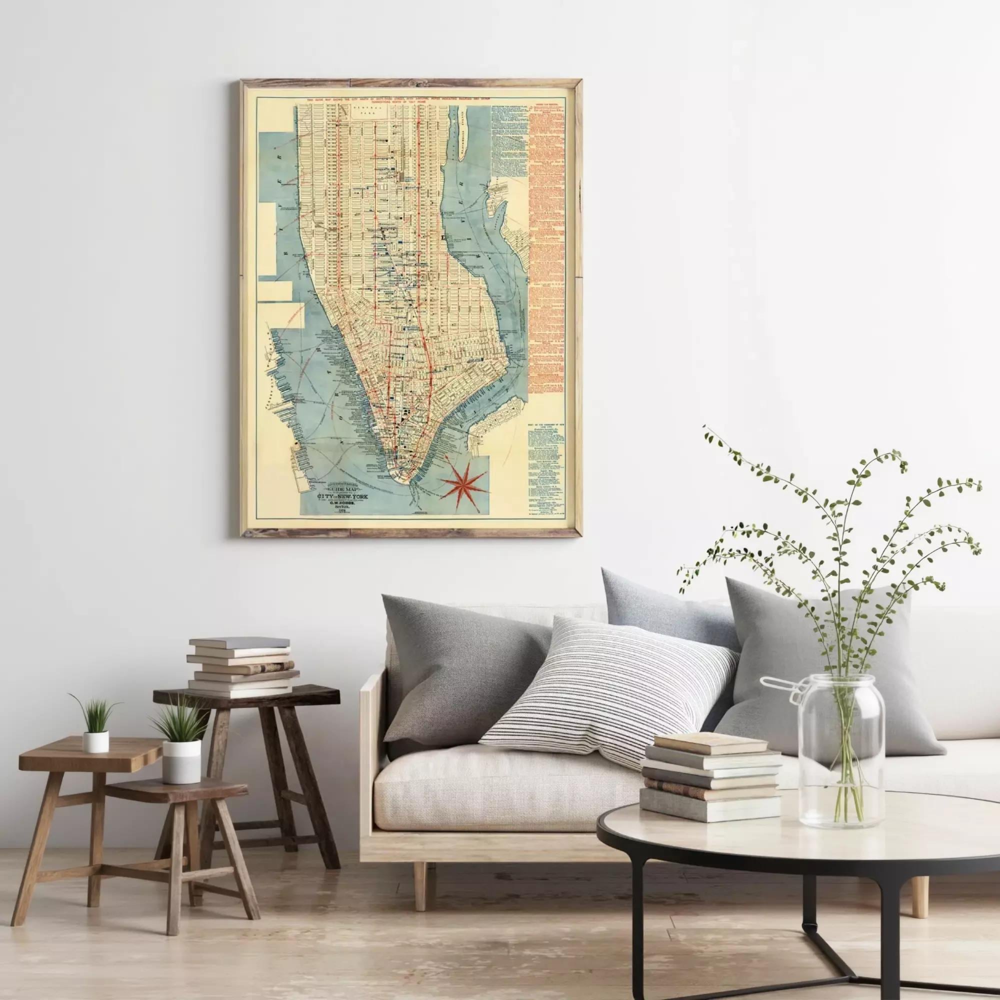 a living room with a large framed map of New York City hanging on the wall above a couch with pillows. There are also some books and a vase with flowers on the couch, creating a cozy and inviting atmosphere.