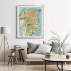 a living room with a large framed map of San Francisco hanging on the wall above a couch with pillows. There are also a few books and decorative items on the couch and coffee table.