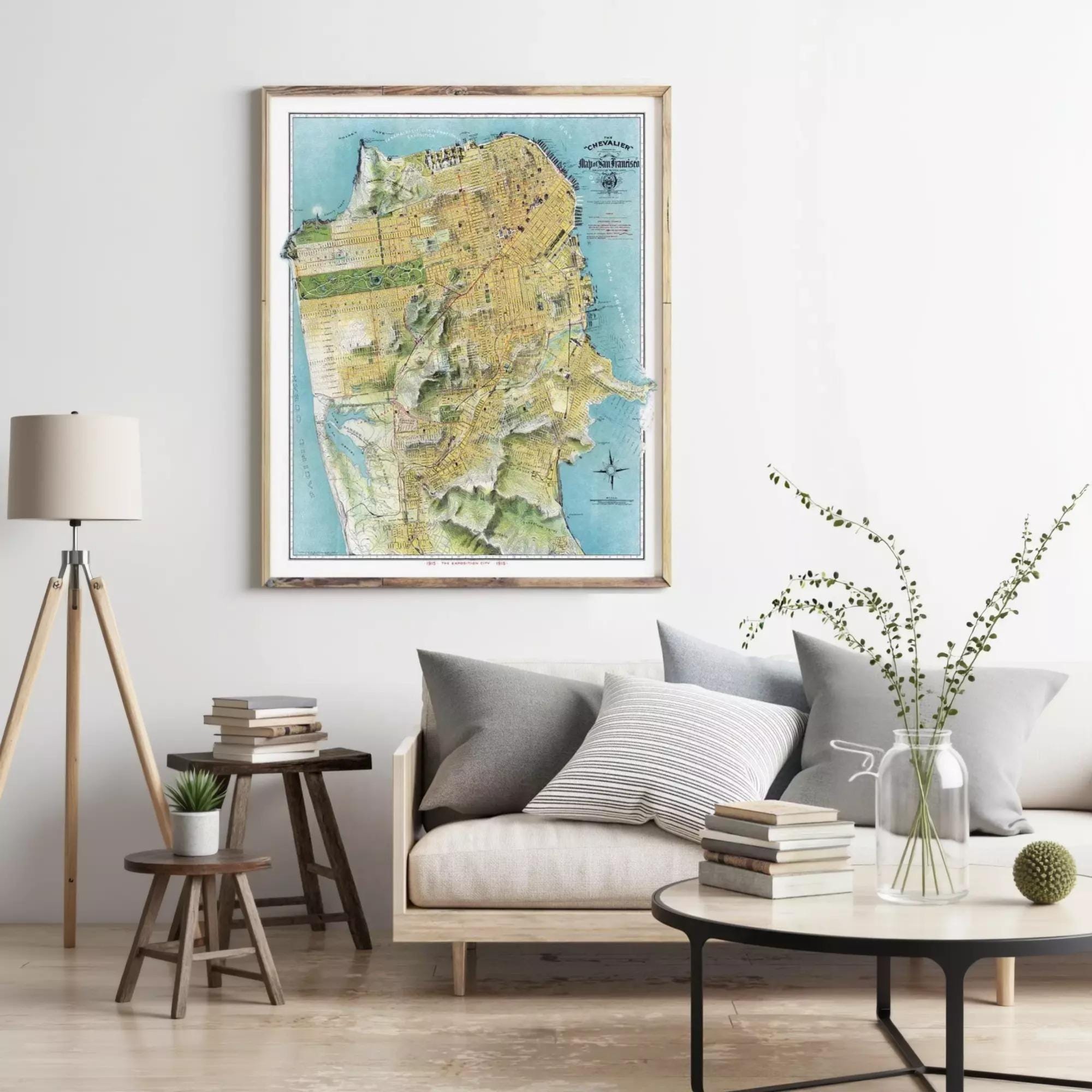 a living room with a large framed map of San Francisco hanging on the wall above a couch with pillows. There are also a few books and decorative items on the couch and coffee table.
