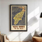 The image is a framed poster depicting a map of Rhodes, Greece, with the text "VISITÉZ RHODES I l'ile des Roses" (Visiting Rhodes, the island of roses) at the bottom.
