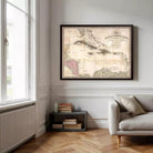 a large framed map of the world hanging on a wall in a room with a window, a couch, and a small table with books.